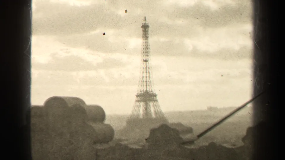 1947 Paris 8mm frame showing a soft distant Eiffel Tower view through dark framing with grain and dust visible.