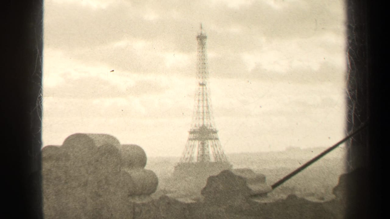 Eiffel Tower centered beyond foreground stonework and a diagonal rod.