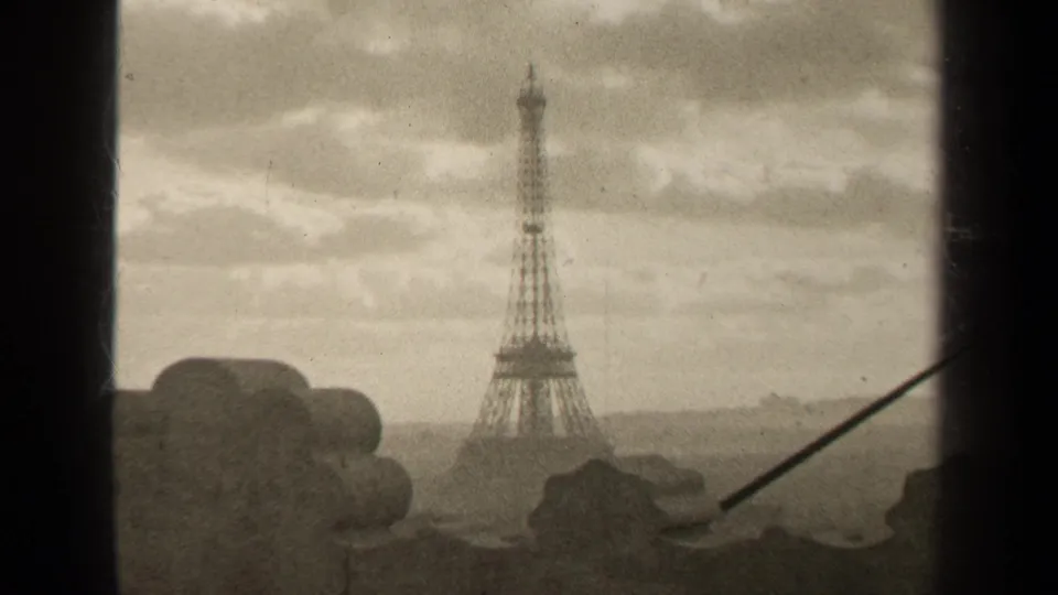 1947 Paris 8mm frame with a darker exposure of the Eiffel Tower, cloudy sky, foreground stonework, and a diagonal rod at right.