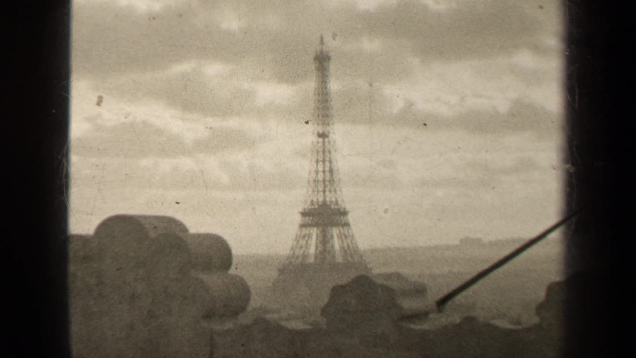 1947 Paris home-movie frame showing the Eiffel Tower through a high window, with cloudy sky and a distant city horizon.