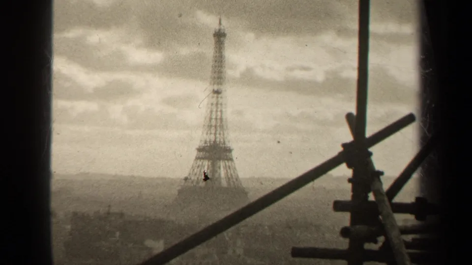 1947 Paris home-movie still showing the Eiffel Tower behind dark vertical window framing and diagonal scaffolding in the foreground.