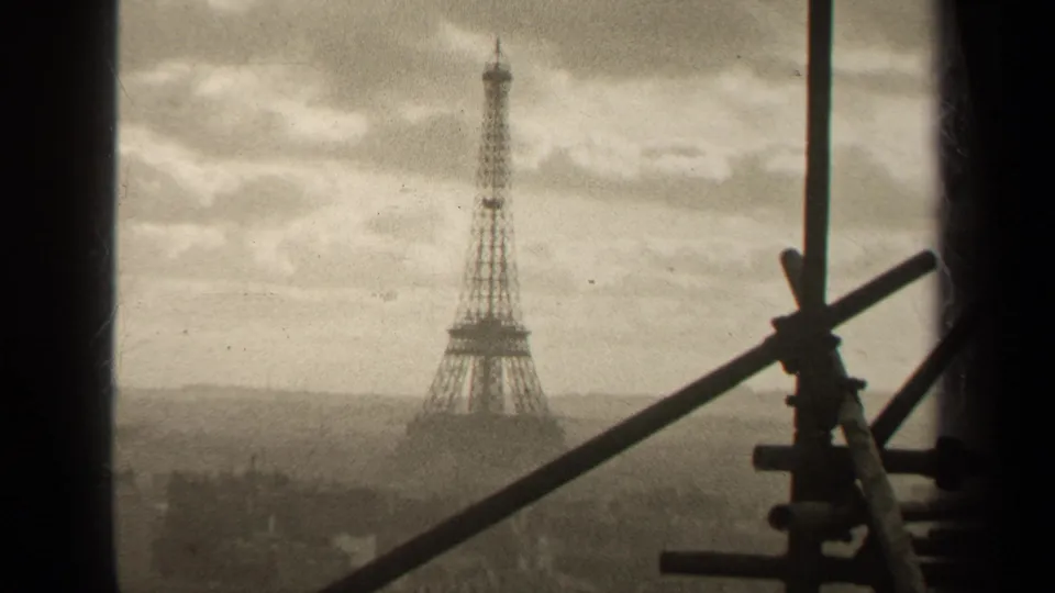 1947 Paris frame showing the Eiffel Tower across a hazy skyline, seen through a window with silhouetted scaffolding at right.