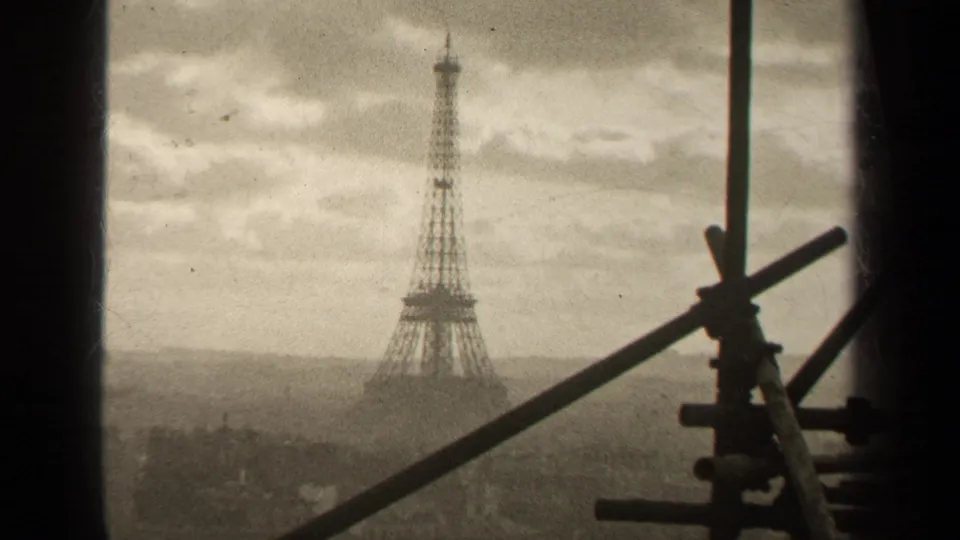 1947 Paris view with the Eiffel Tower centered in haze, seen past diagonal scaffolding and a dark window or structural edge.