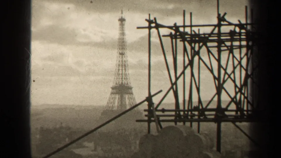 1947 Paris frame with the Eiffel Tower beyond the city skyline and a dense scaffold structure at right.