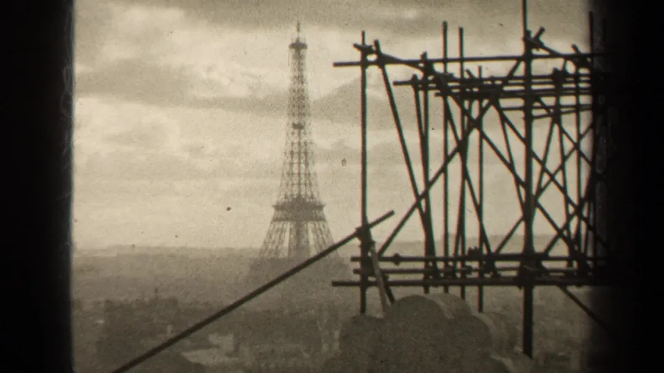 1947 Paris home-movie view of the Eiffel Tower with heavy foreground scaffolding and a hazy cityscape below.