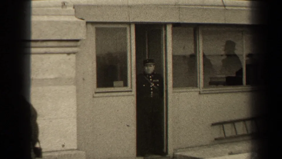 Paris 1947 home-movie frame returning to the uniformed man at the doorway, with windows and exterior ladder visible.