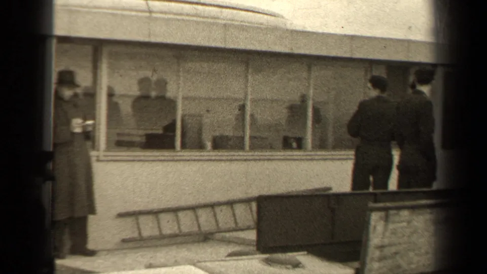 Two civilians stand outside the Paris building near a leaning ladder, while interior silhouettes are visible through the windows.
