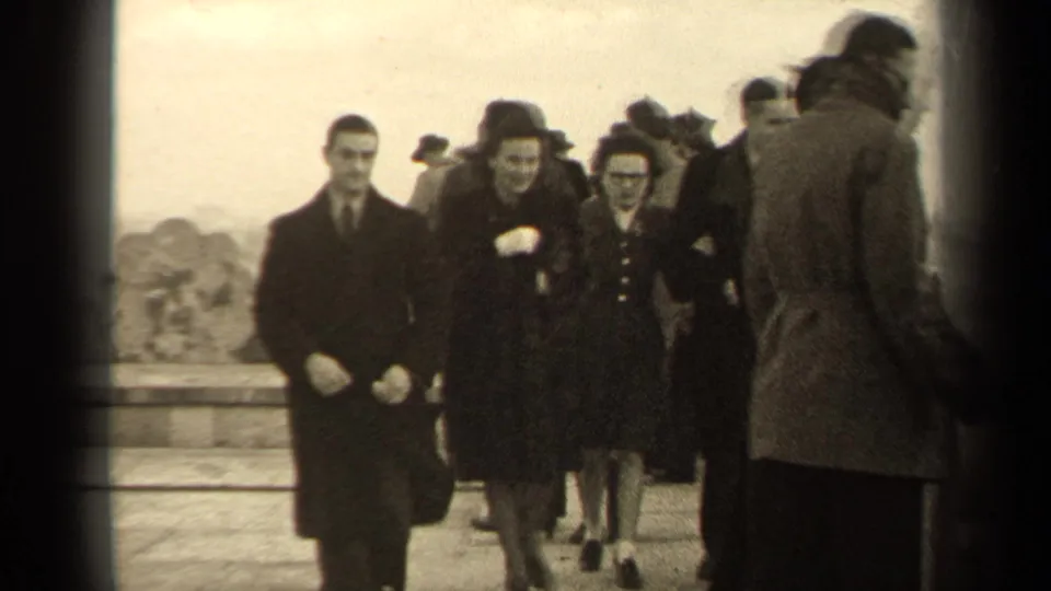 A small group of adults smiles and walks toward the home-movie camera during a windy 1947 Paris sightseeing stop.