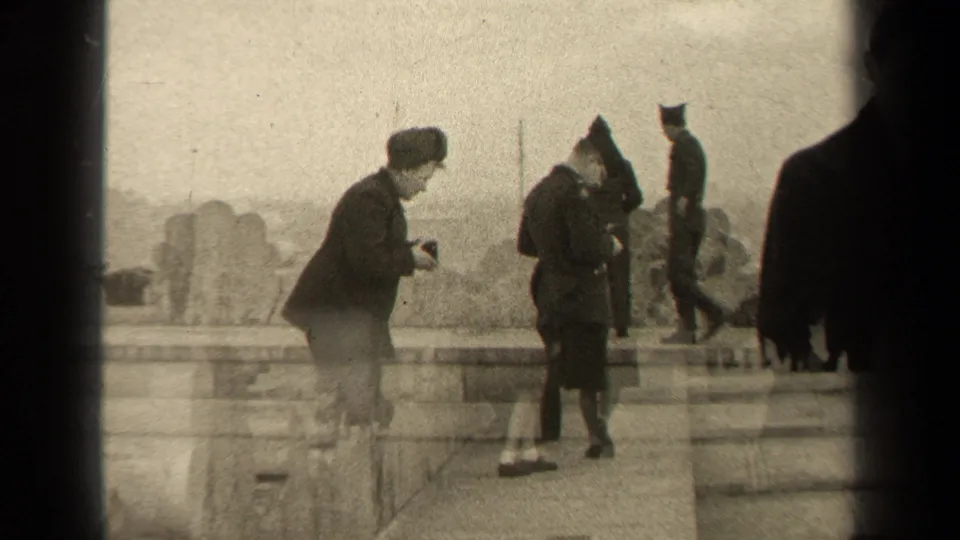 1947 Paris frame showing a camera-holding woman, a uniformed man, and nearby adults on an outdoor stone promenade.