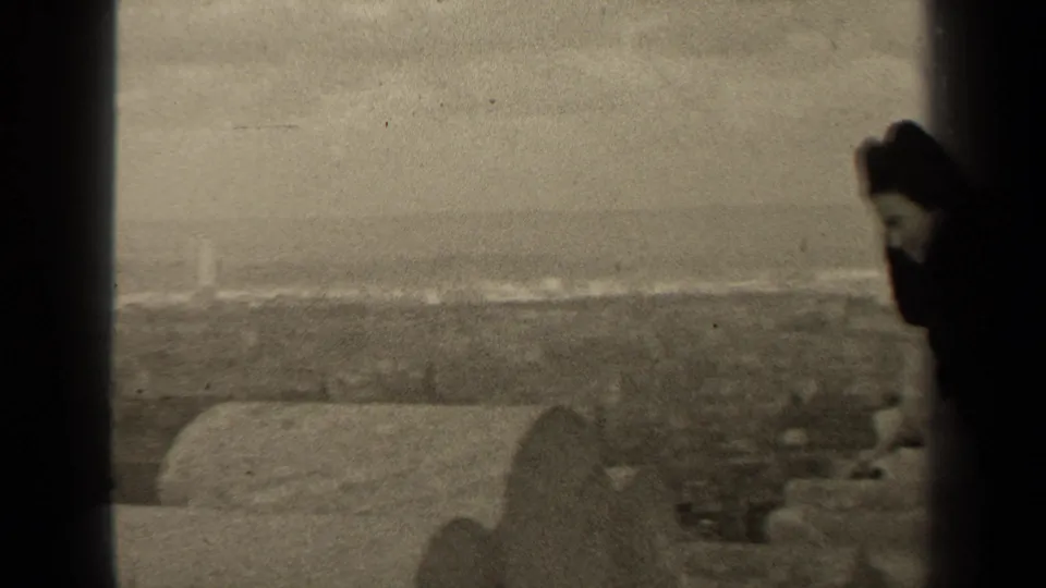 A woman in dark clothing stands near the side of the frame above a hazy Paris cityscape in 1947 footage.