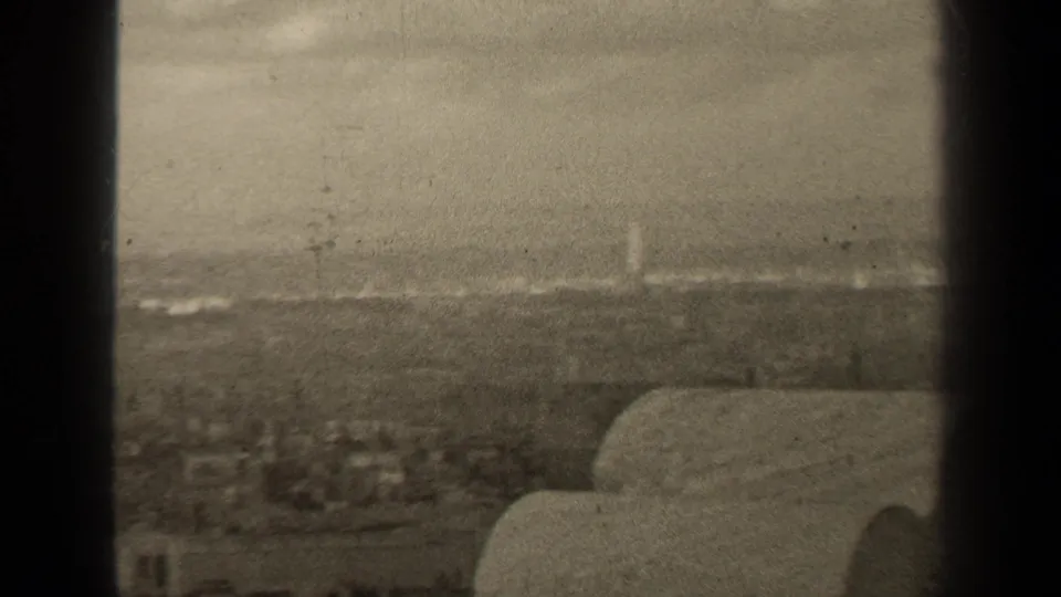 A high vantage view across Paris shows rooftops and a distant horizon, partly blocked by dark vertical film-frame edges.