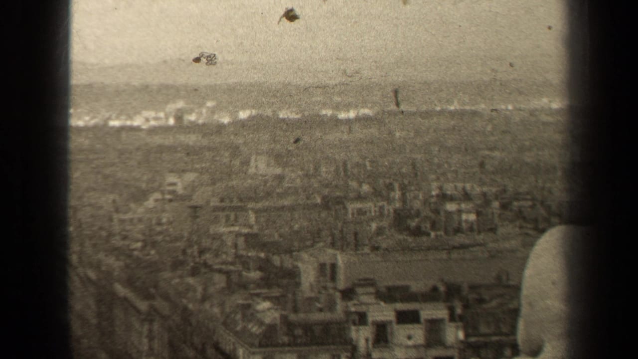 Soft aerial view over dense Paris rooftops with dark frame edges and distant haze.