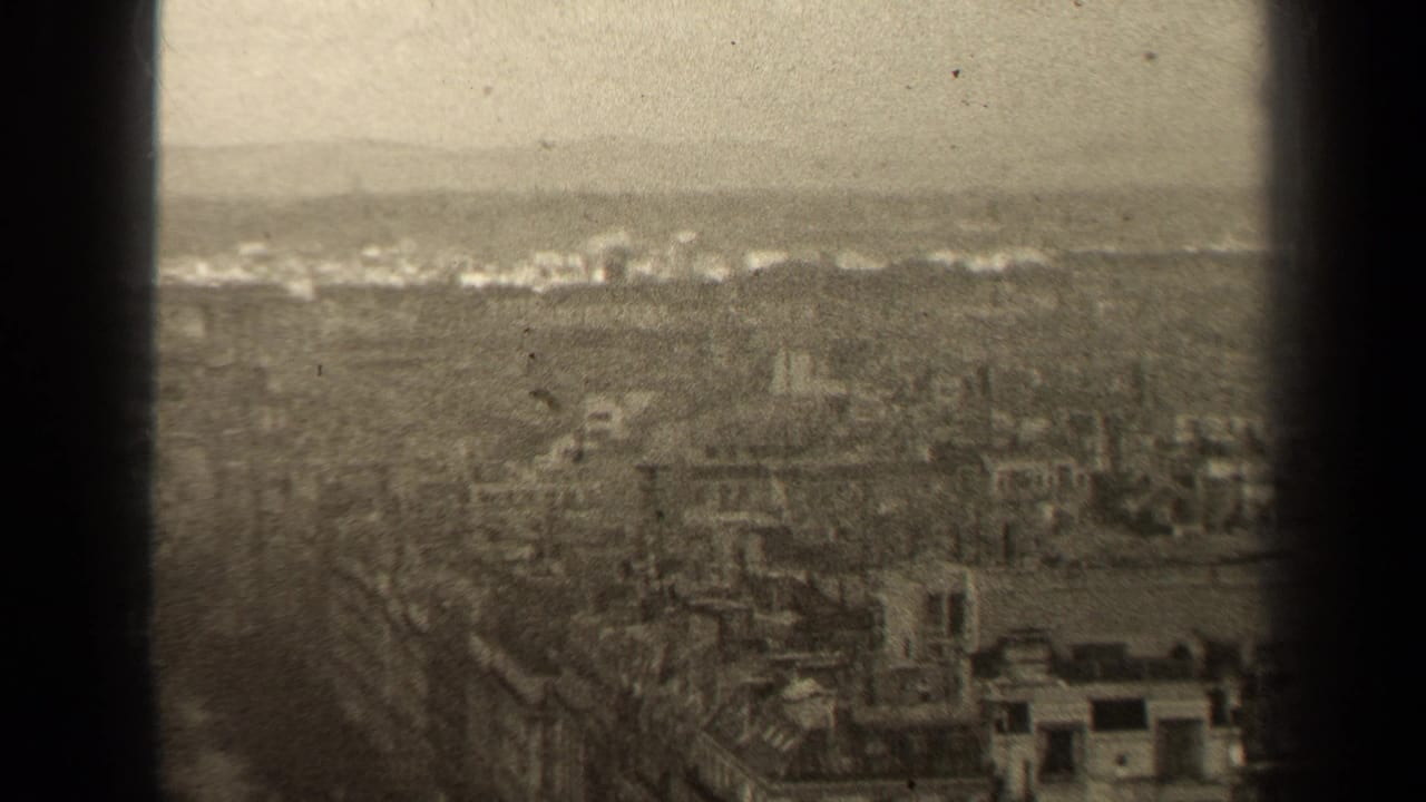 1947 Paris cityscape from an elevated viewpoint, with rooftops fading into haze and a dark frame bar crossing the view.