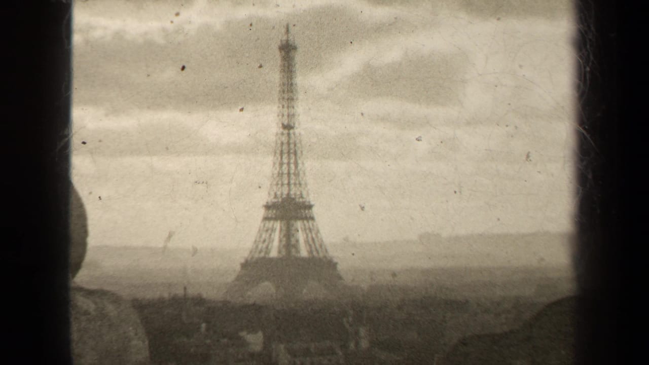 1947 8mm Paris view of the Eiffel Tower through a window, with soft sepia tone, cloudy sky, and faint rooftops below.