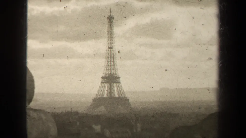 Final 1947 Paris frame holds on the Eiffel Tower through a window, with pale clouds, distant rooftops, and archival 8mm texture.