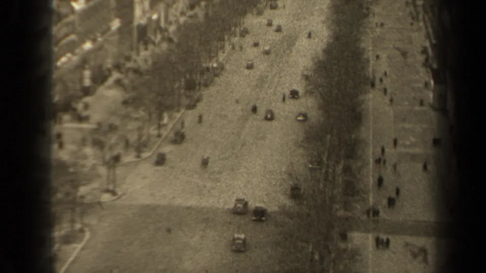 1947 Paris boulevard seen from a high vantage point, with mid-century cars and distant pedestrians beside tree rows.