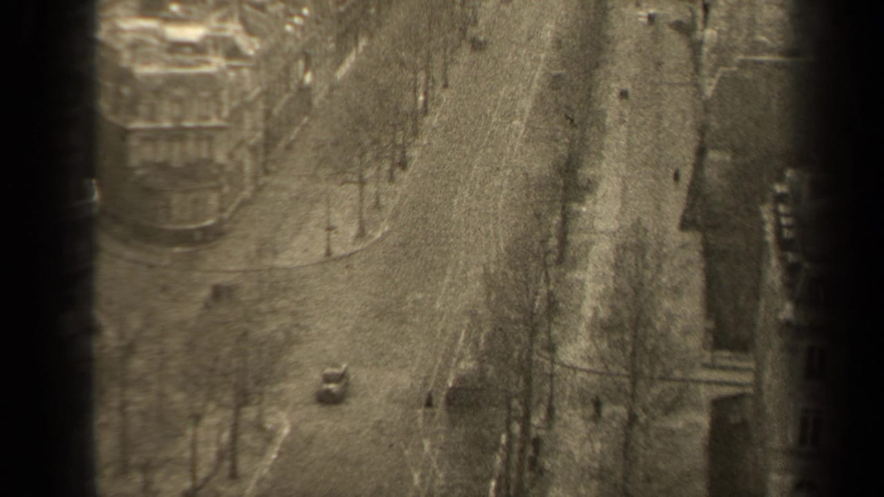 High-angle view of a quiet city street with bare trees, pedestrians, and a small car.