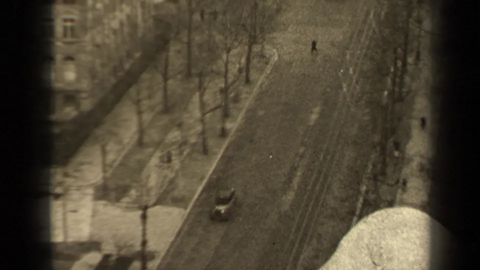 Late frame from the 1947 Paris clip showing the same quiet boulevard, distant pedestrians, one car, and heavy edge vignetting.