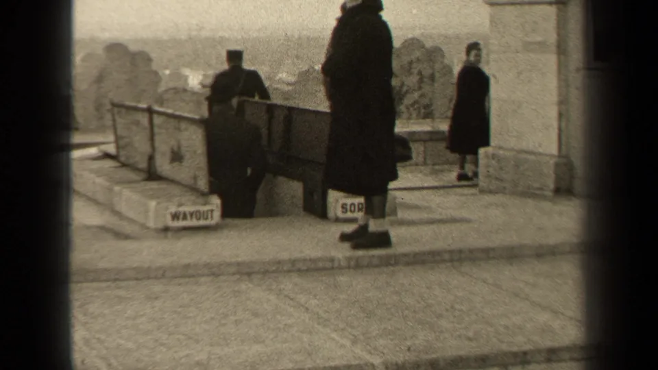 At a Paris viewing area in 1947, visitors in coats stand near a railing with a visible WAYOUT sign and distant scenery.