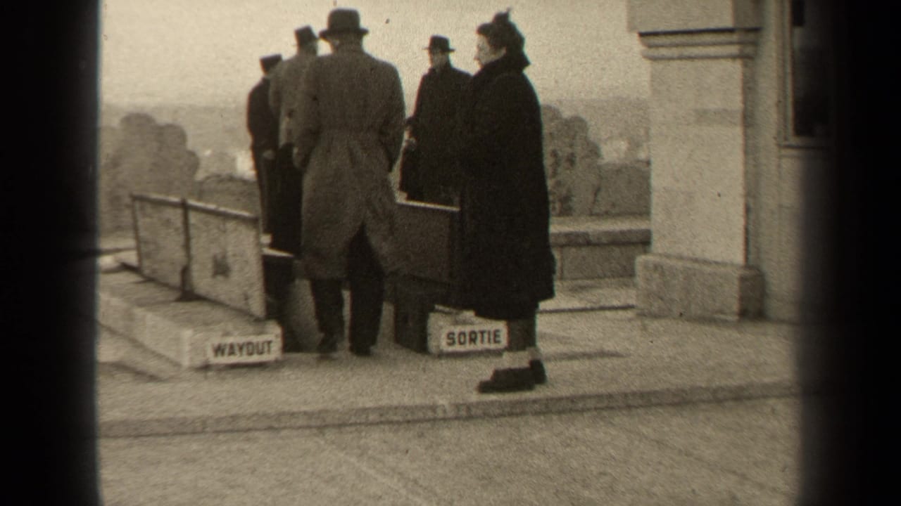 Adults in coats and hats stand near WAYOUT and SORTIE signs by a public exit.