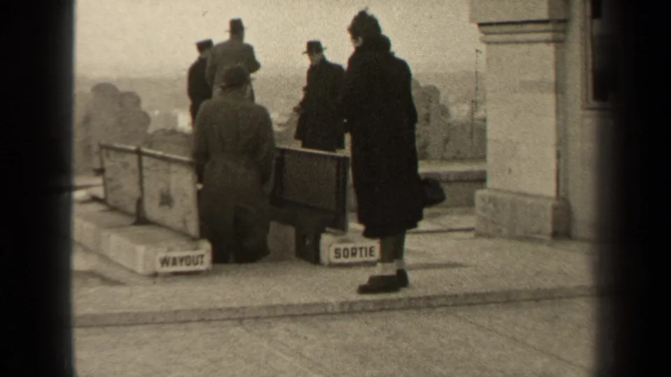 Paris 1947 home-movie frame with visitors near a barrier and visible WAYOUT and SORTIE exit signs.
