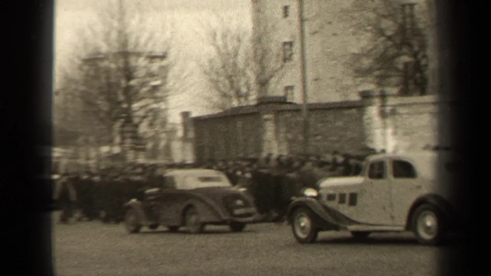 1947 Paris street view with rounded mid-century cars, pedestrians along the roadway, bare trees, and buildings in the background.