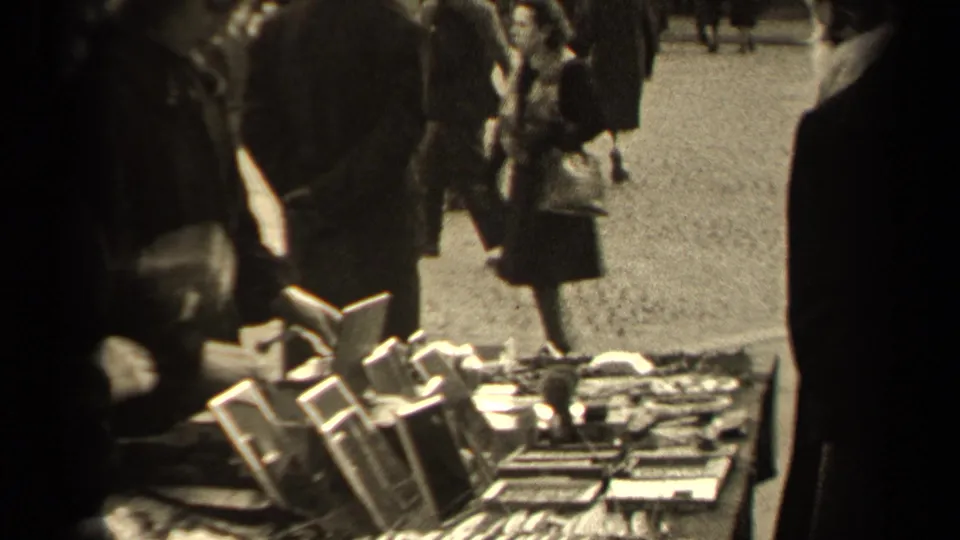 1947 Paris street-market view with shoppers near displayed goods and pedestrians crossing the background.