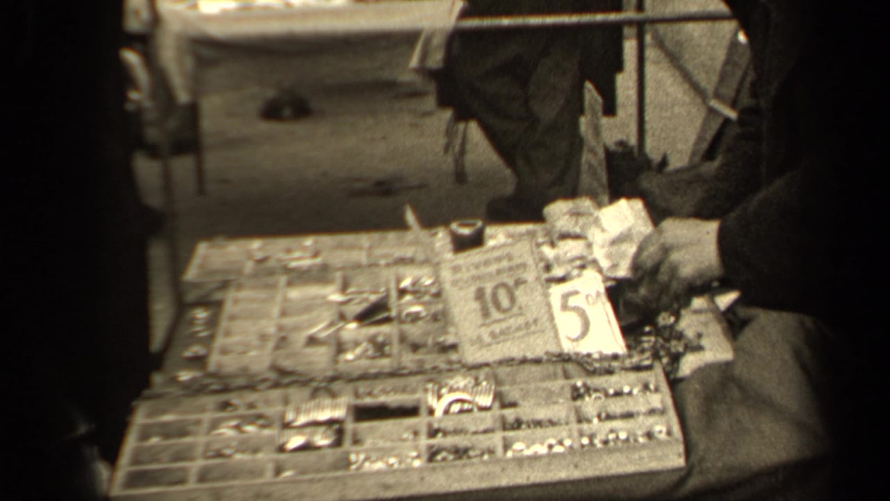 Market stall tray with small goods, price cards, and adult hands nearby.