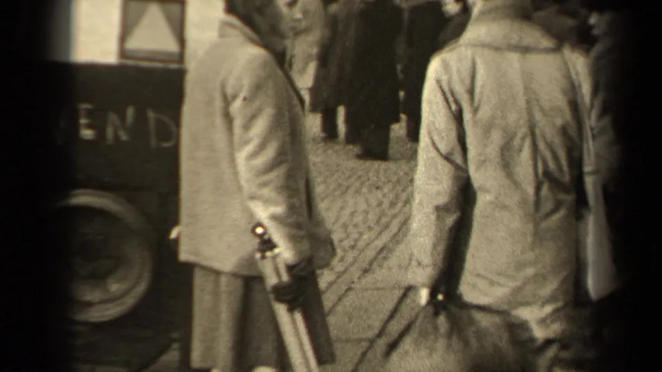In the stated Paris street scene, two pedestrians walk away on cobblestones near a cart or vehicle side and market activity.
