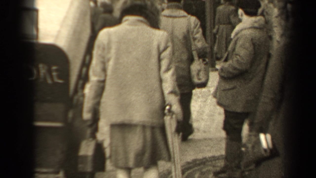 Back view of pedestrians in coats walking through a crowded street.