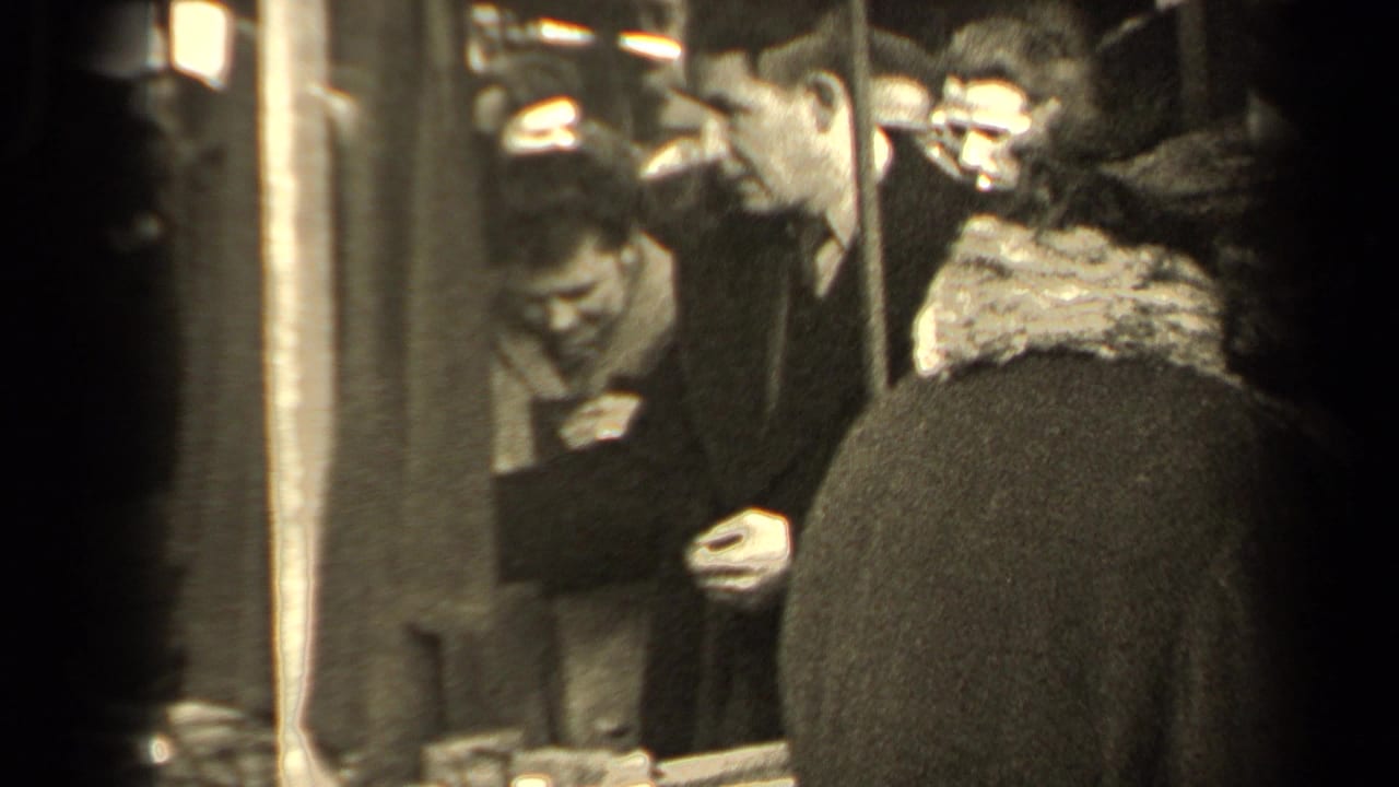 Crowded transit interior with people in dark coats standing near vertical poles.