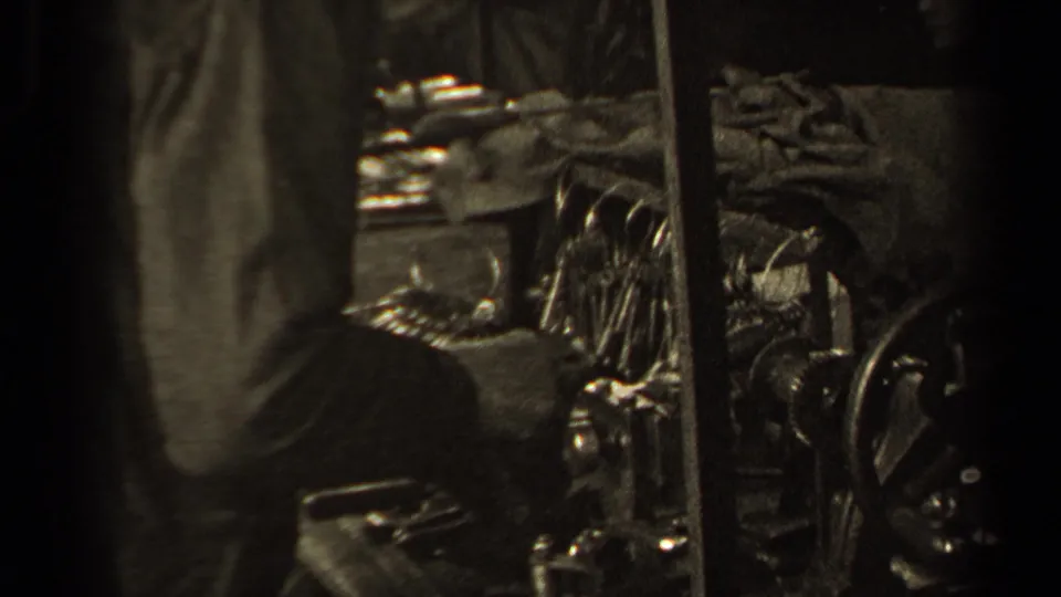 Close home-movie view of the polishing station area, with a standing figure, clustered equipment, and reflective metal objects.