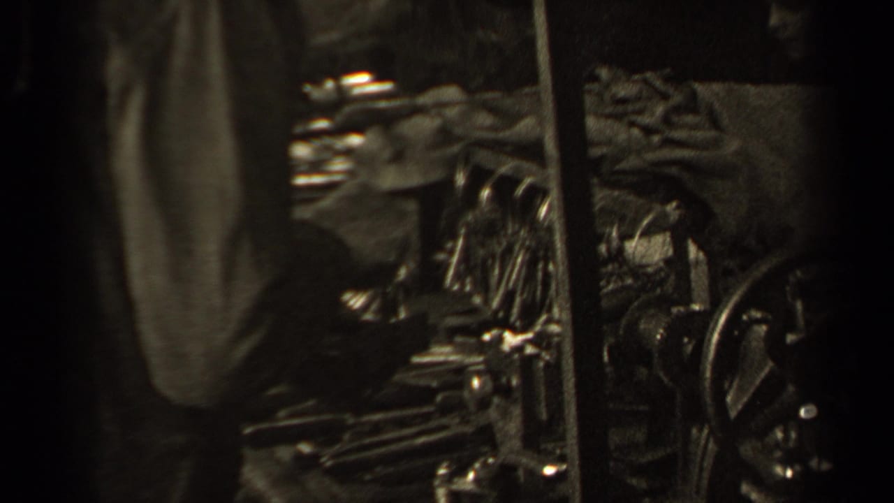 Close view of a coat sleeve beside dark metal equipment and stacked material.