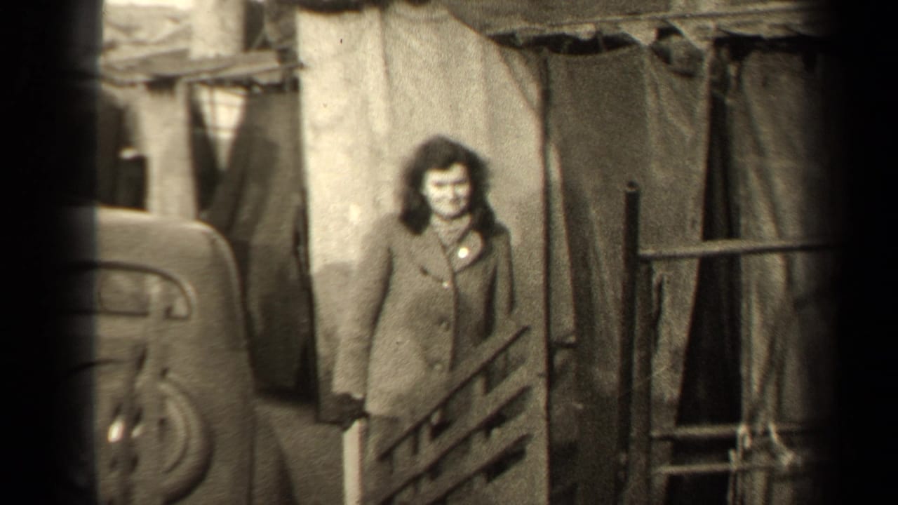1947 Paris street frame with a woman looking toward the camera beside a car and makeshift-looking coverings.
