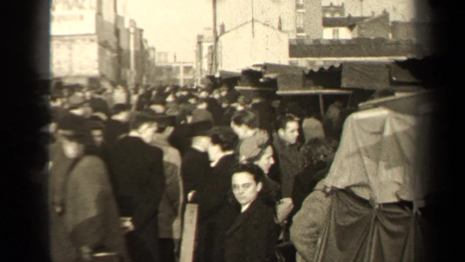 1947 Paris street scene showing a dense crowd of pedestrians between covered street structures and city buildings.