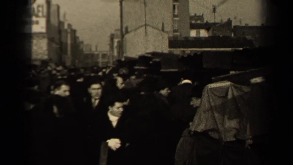 1947 Paris street scene with coat-clad pedestrians moving through a crowded market-like area beside stalls and wall advertising.