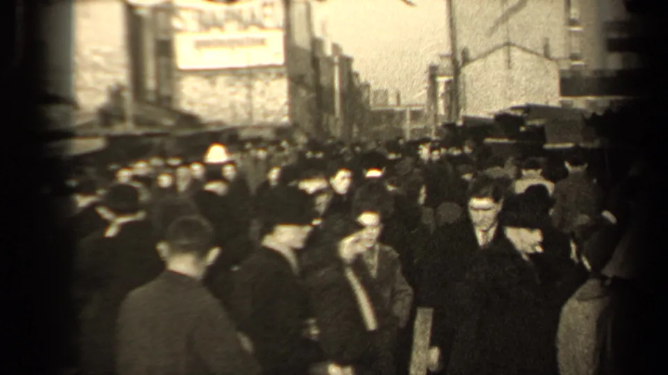 1947 Paris street view showing pedestrians in overcoats below a large wall advertisement and market-side congestion.