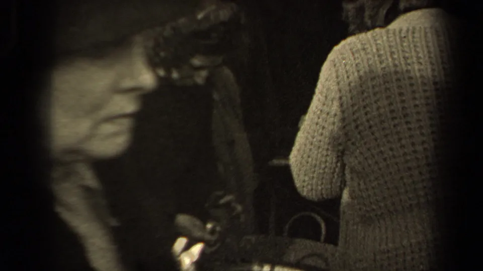 A blurred passerby crosses the foreground while a woman in a knit sweater stands near the basket in the Paris street crowd.