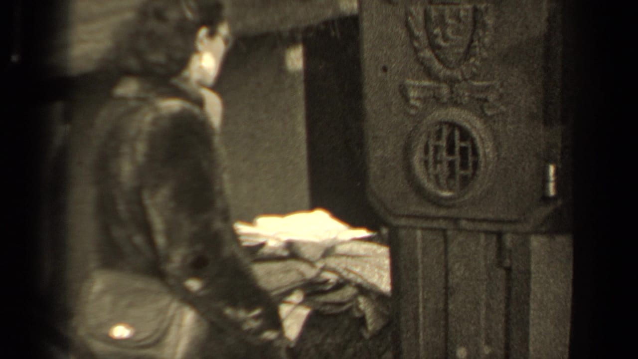 Woman stands side-on near a decorative structure with fabric or clothing nearby.