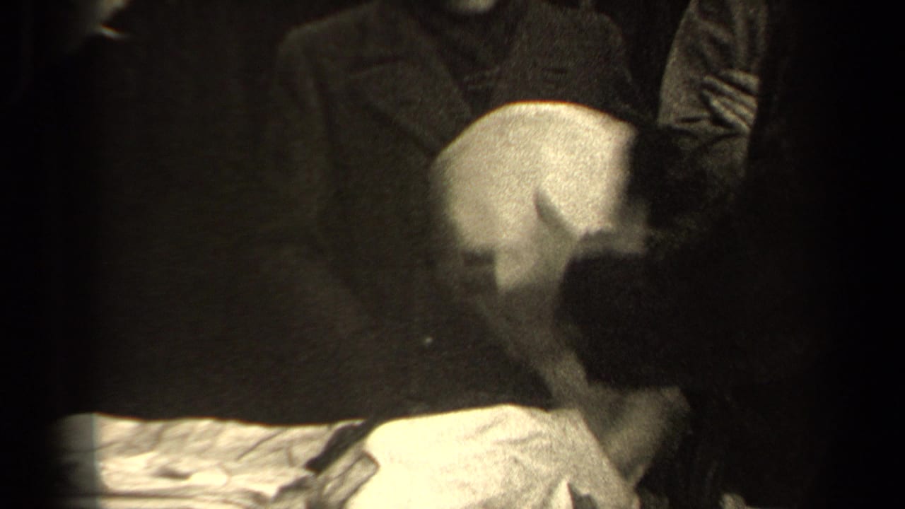 A person leans over a pale cloth or garment as bundled adults cluster around the street-side purchase area in Paris.