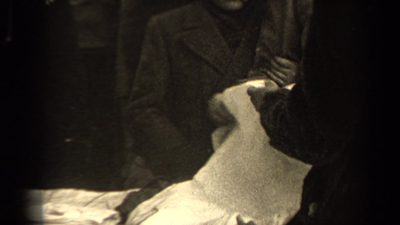 Gloved hands handle pale cloth while dark-coated figures stand close together in 1947 Paris footage.