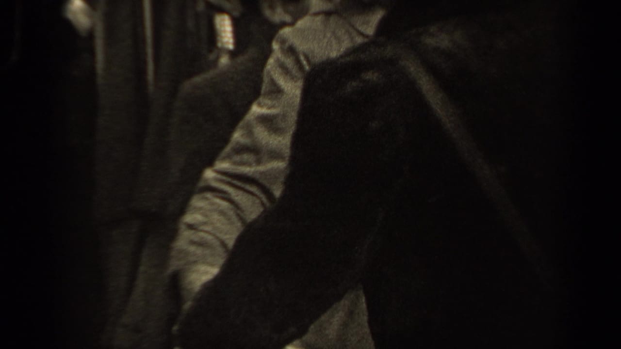 An adult figure leans toward a light shirt as another dark-clad person partially blocks the view in 1947 Paris footage.