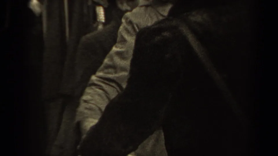 An adult figure leans toward a light shirt as another dark-clad person partially blocks the view in 1947 Paris footage.