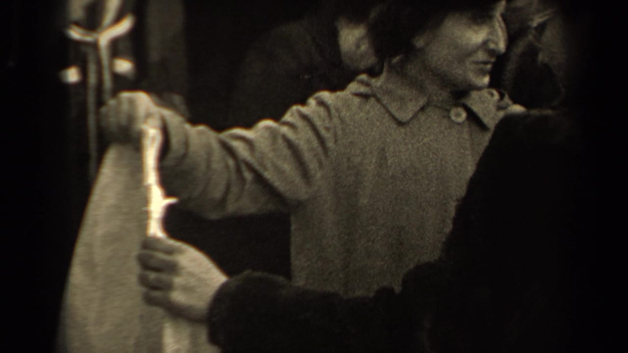 In a 1947 Paris market scene, two adult women in coats and hats focus on a pale garment while people stand close around them.