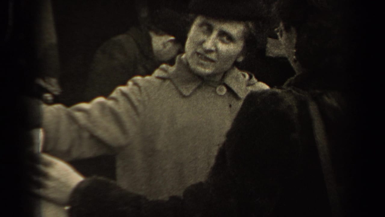 A woman in a coat gestures beside another person holding fabric in a crowded market.