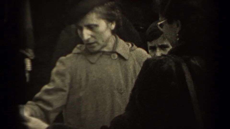 The 1947 Paris market view shows a woman in a light coat looking down toward the garment as people cluster closely nearby.