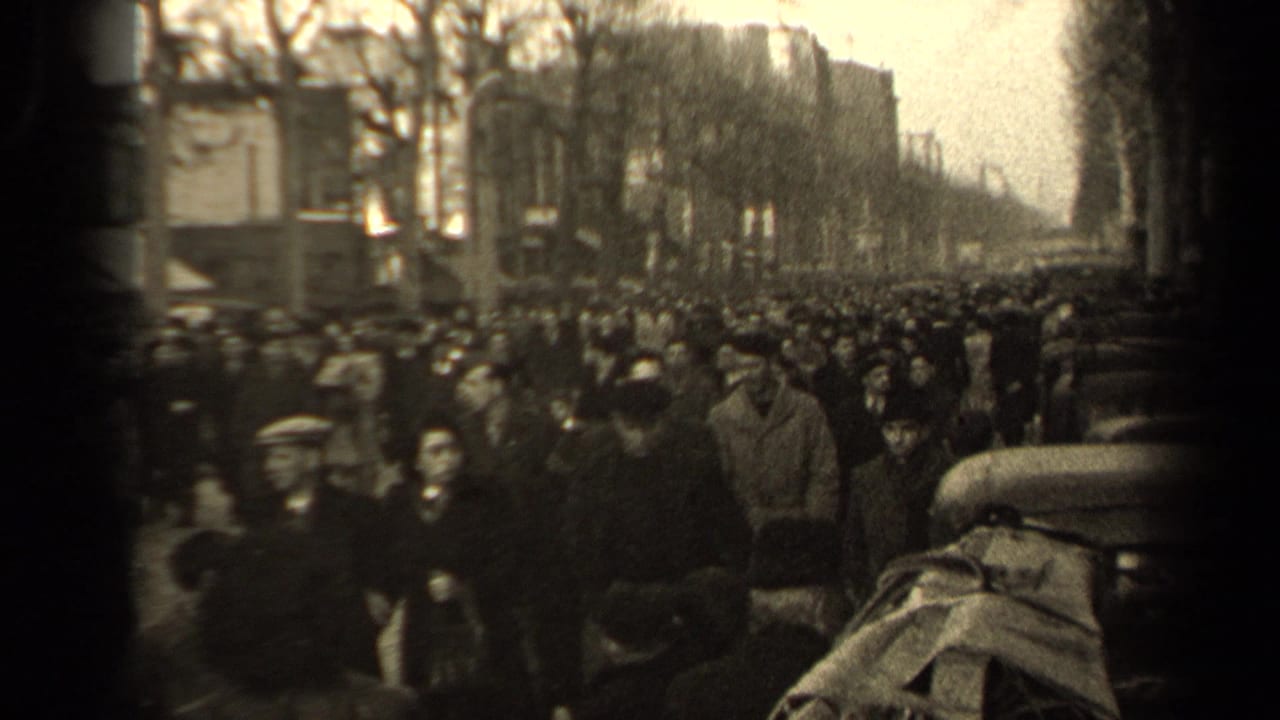 Paris street crowd in 1947, with pedestrians in period coats and hats passing a partially obscured camera viewpoint.