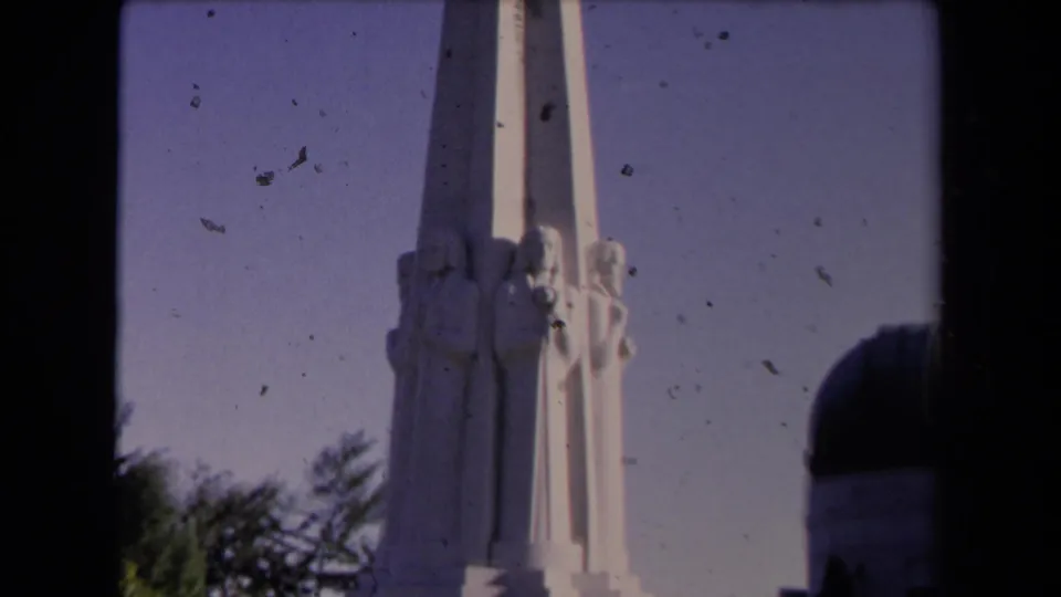 Closer 1967 view of the white sculpted pillar on the Griffith Observatory grounds, with trees and part of the dome visible.