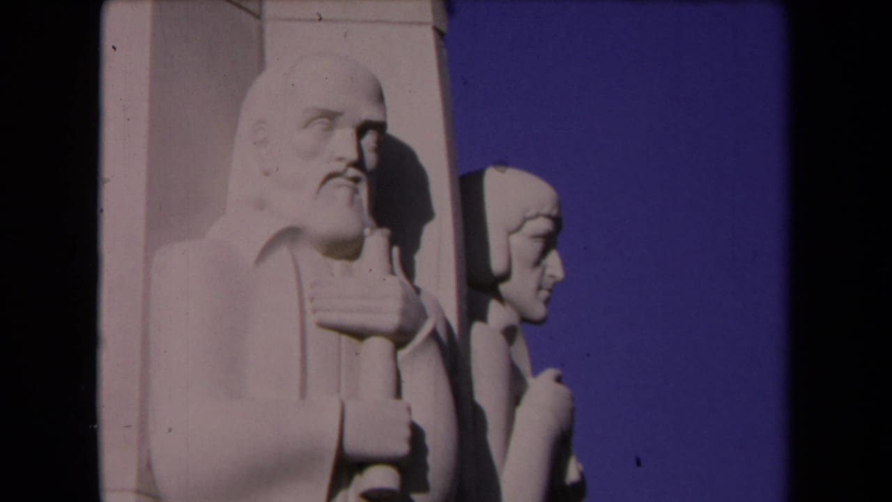 Similar view of two pale stone figures with sky behind them.