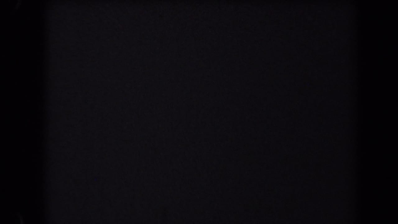 Mostly dark frame area with visible film grain and faint edge detail.